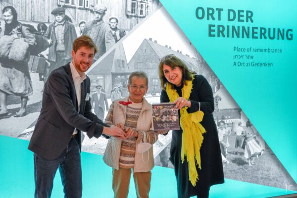 9000. Besucherin Ingrid Kess mit Jonathan Coenen und Dr. Sybille Krafft Erinnerungsort BADEHAUS